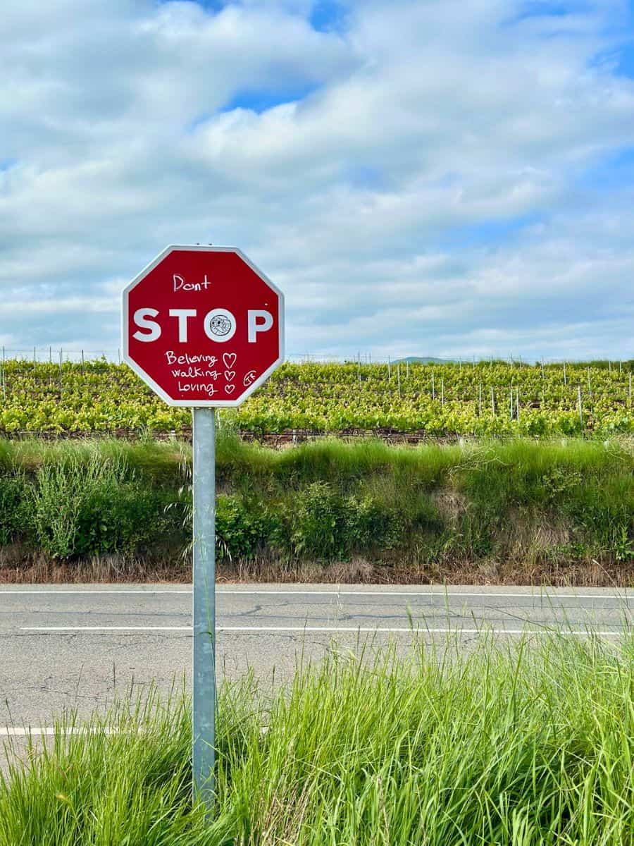 A stop sign along the Camino with writing to read, "don't STOP believing." One of the most important Camino packing tips is to not pack your fears.