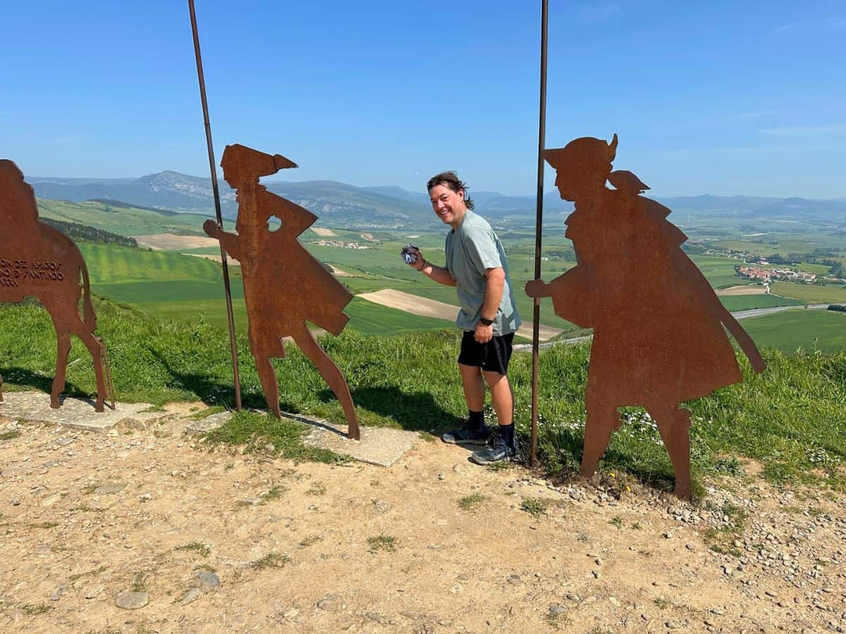 Steve posing for a photo with iron statues at Alto del Perdon. 