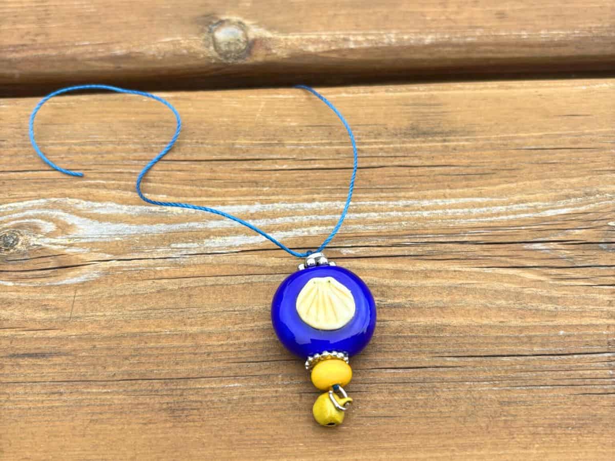A handmade glass charm with a Camino shell - gifted to us by a Camino friend.